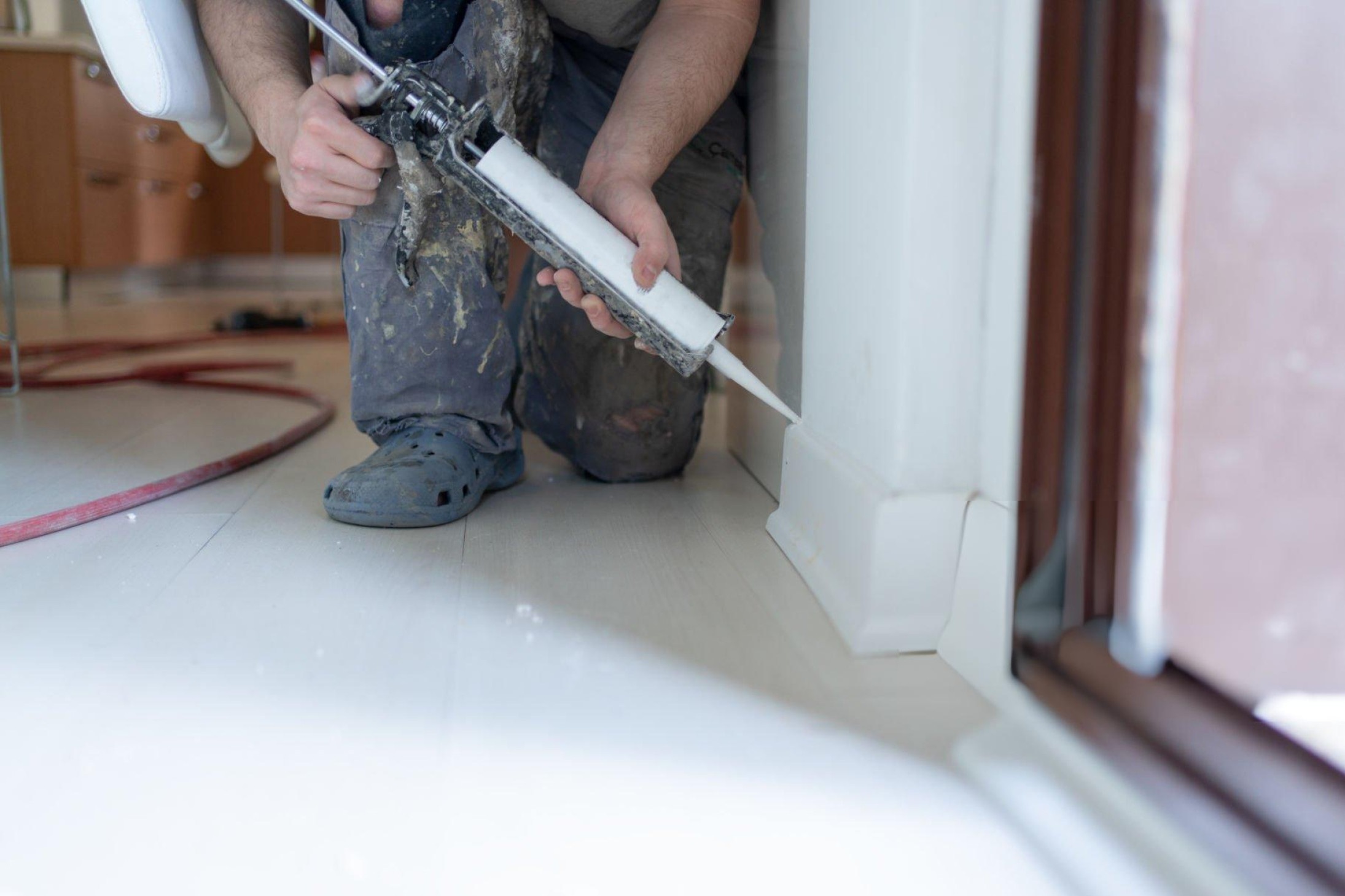 Hero image showing a caulk gun, silicone/acrylic/polyurethane tubes, and a clean bead along a bathtub edge