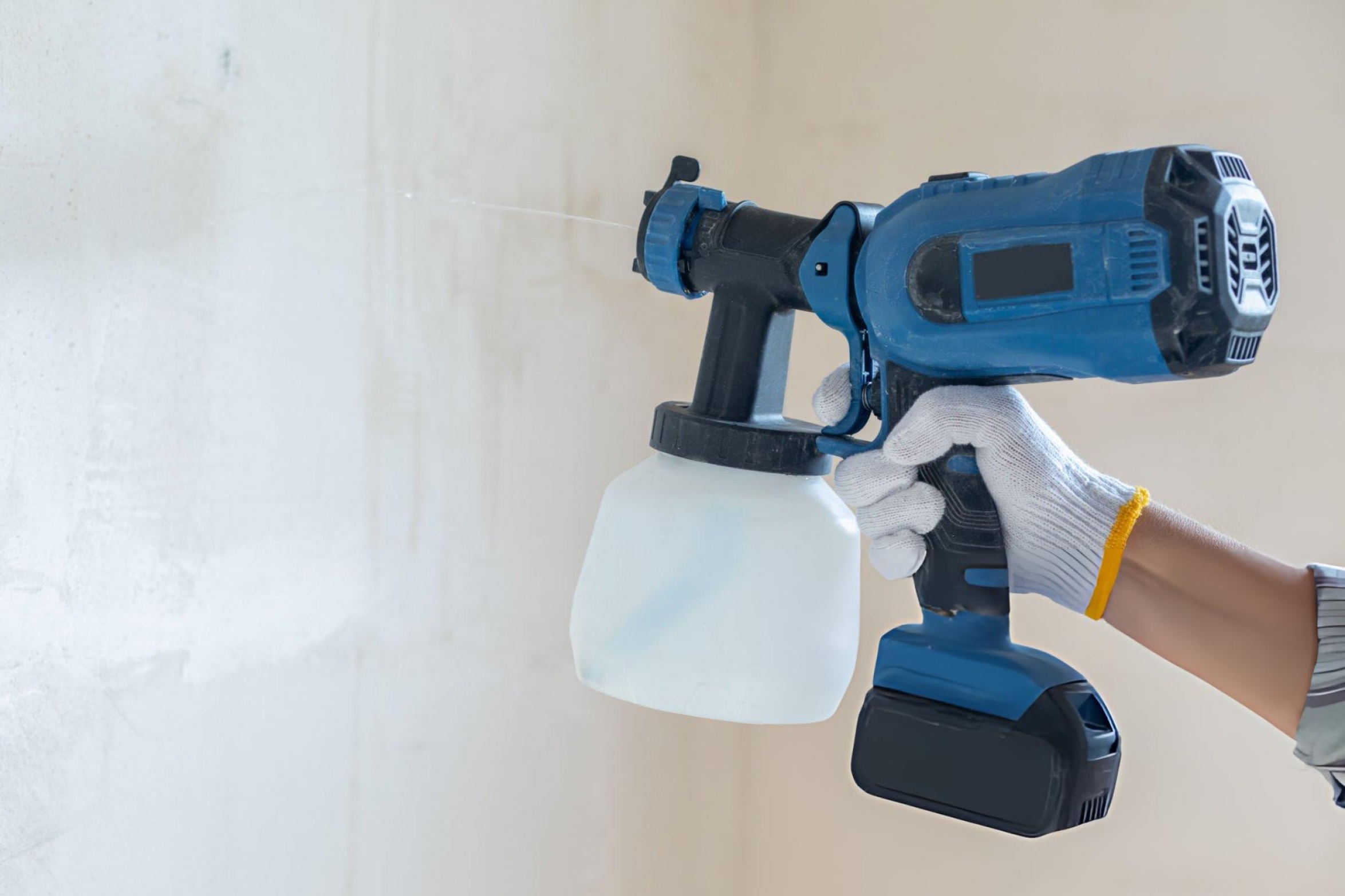 Professional using airless paint sprayer with proper safety equipment demonstrating correct technique for even paint application