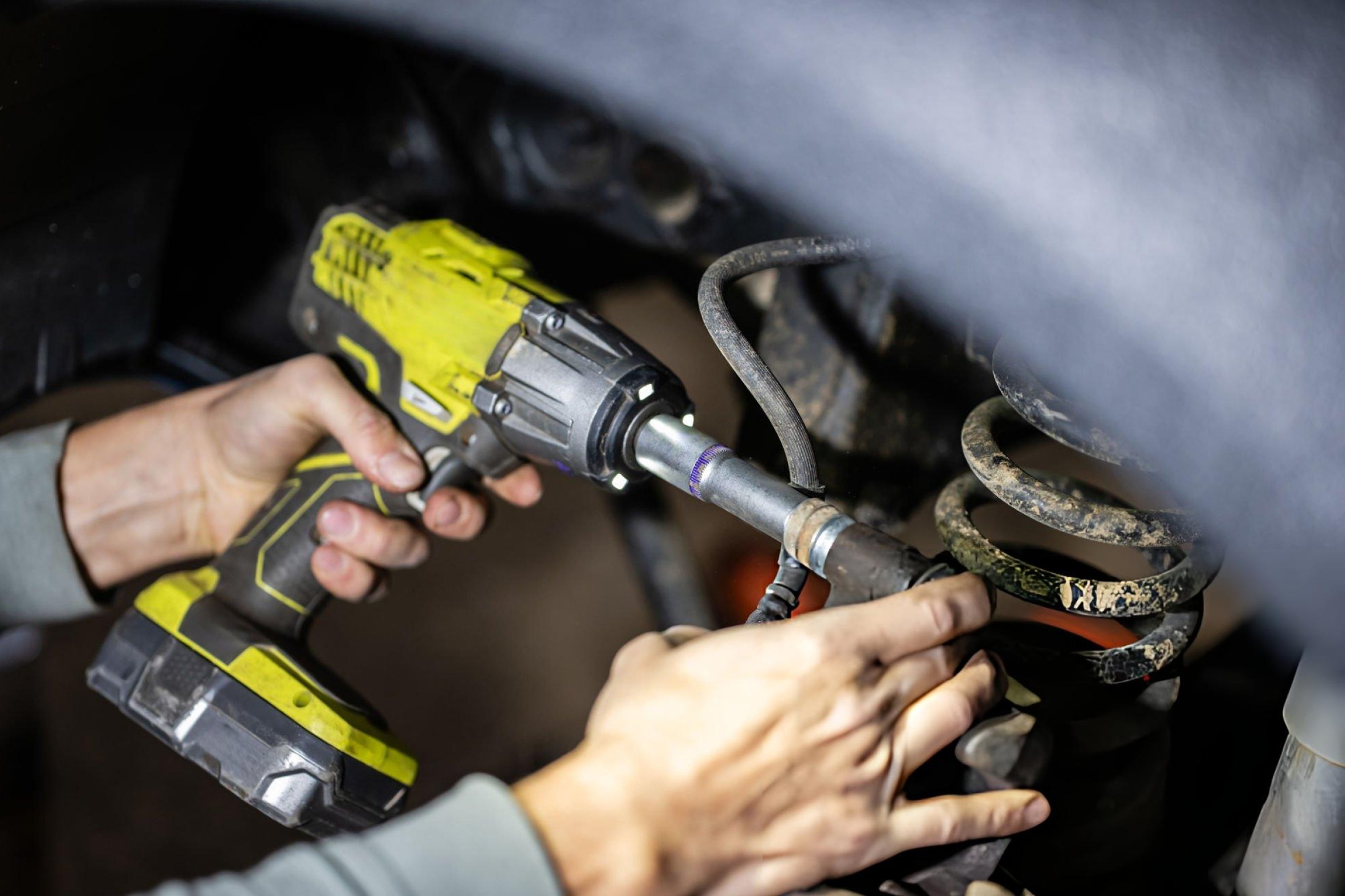 Side-by-side comparison of electric cordless impact wrench and pneumatic air impact wrench in professional workshop setting