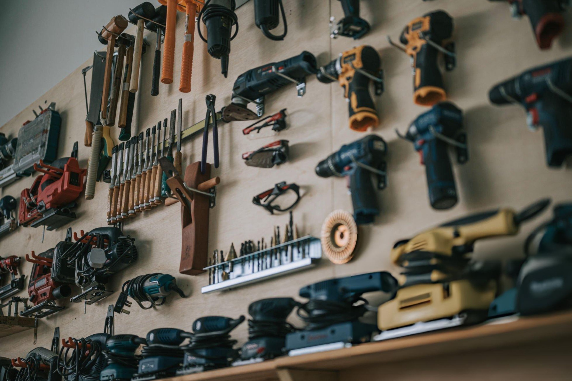 Essential woodworking power tools including table saw, cordless drill, orbital sander, and router on a professional workshop bench