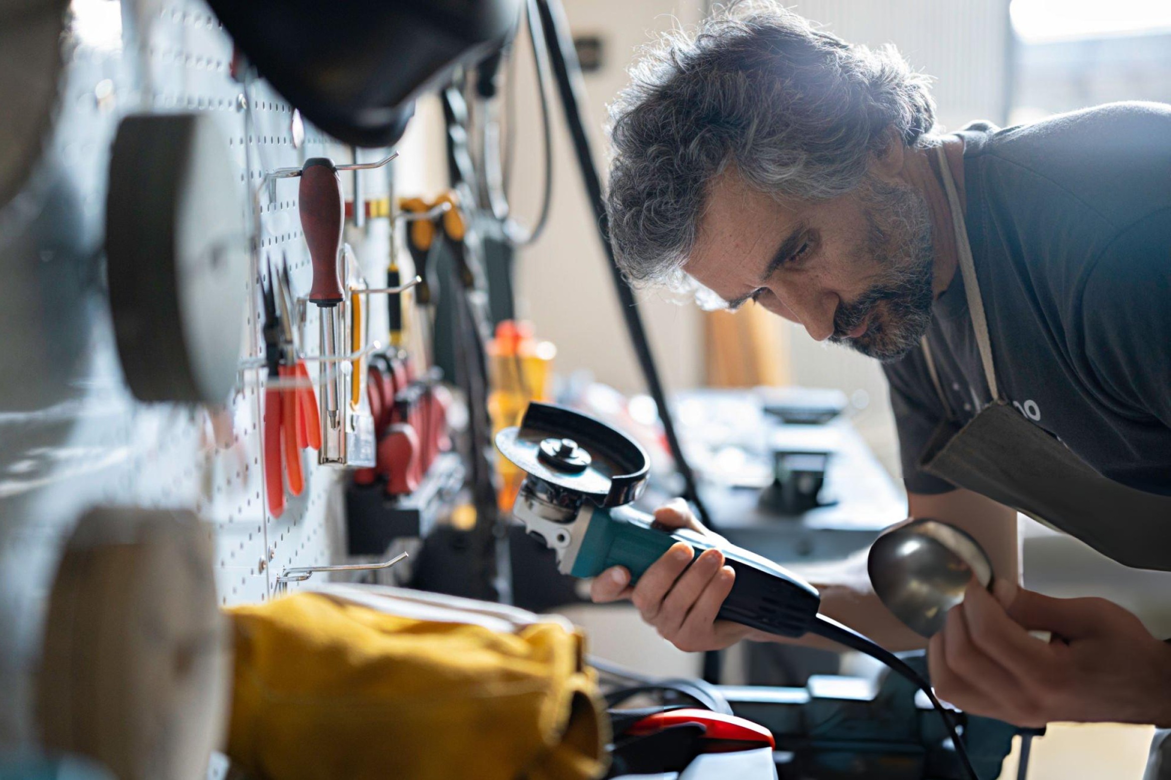 Oscillating multi-tool cutting through wooden door frame during home renovation with various blade attachments displayed nearby