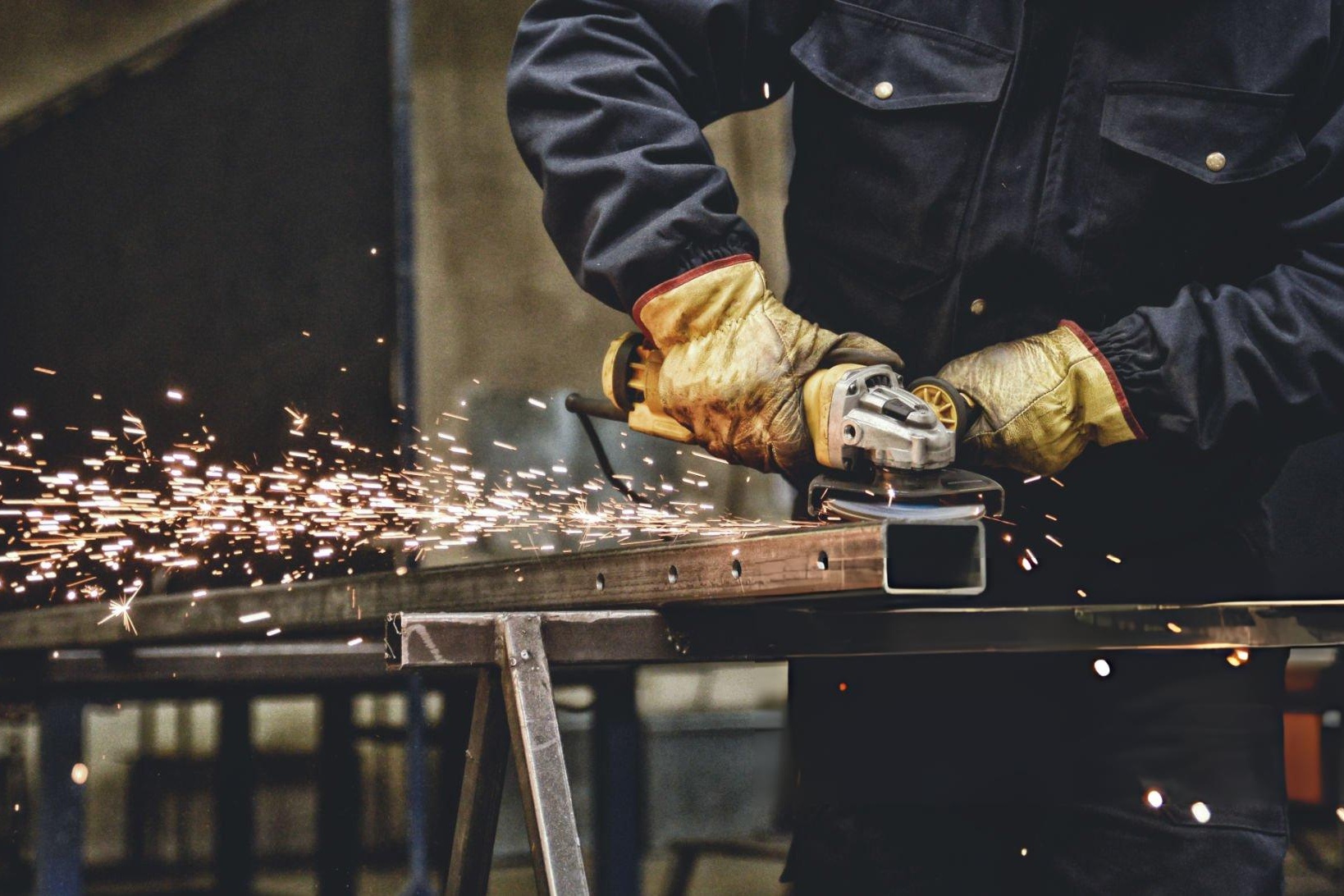 Angle grinder safety setup with guard installed and full PPE while grinding metal with sparks controlled