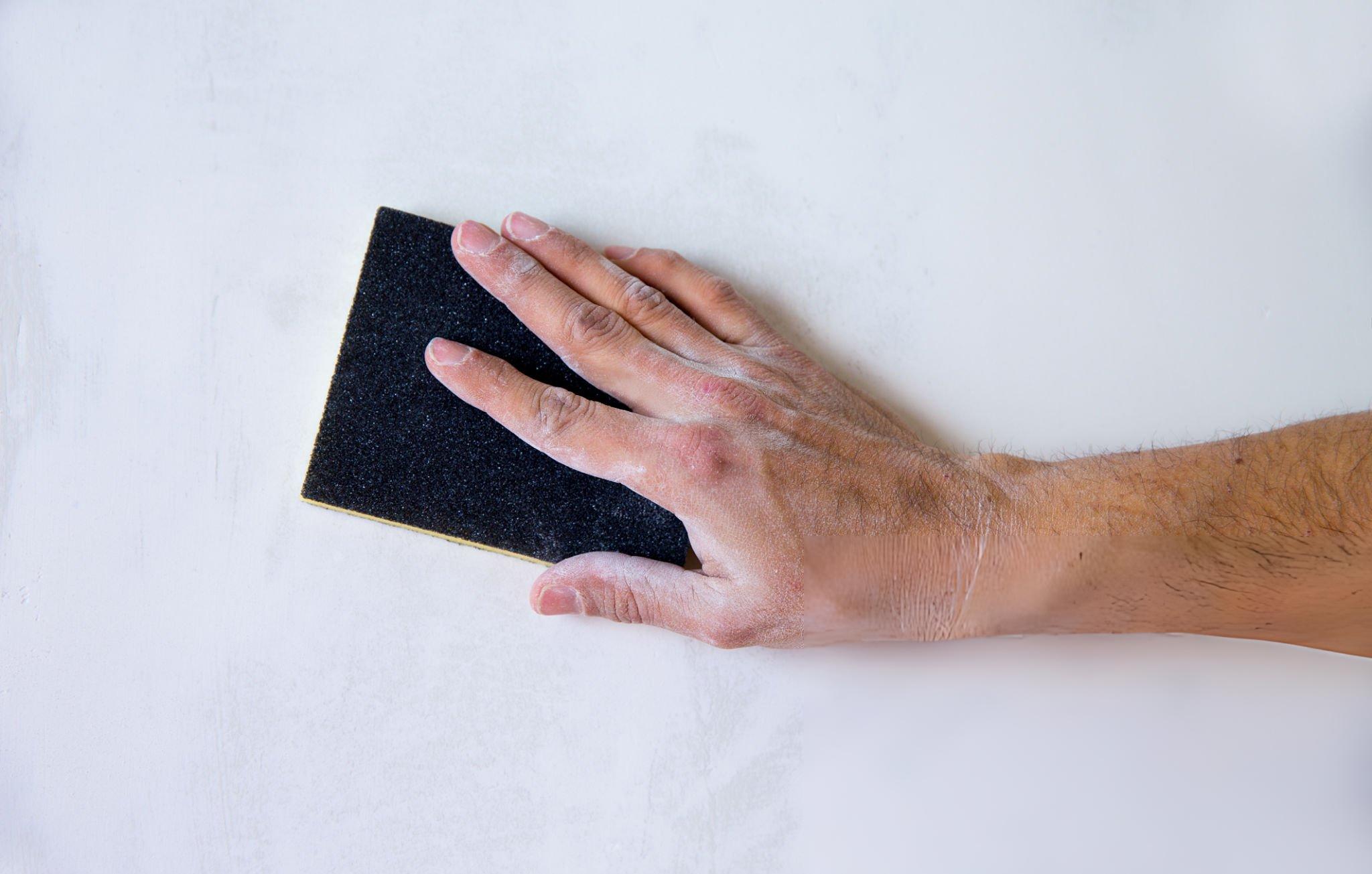 Esponja de lijar para paneles de yeso versus papel de lija en un banco de trabajo para lijar la masilla para juntas y preparar las paredes para pintar.