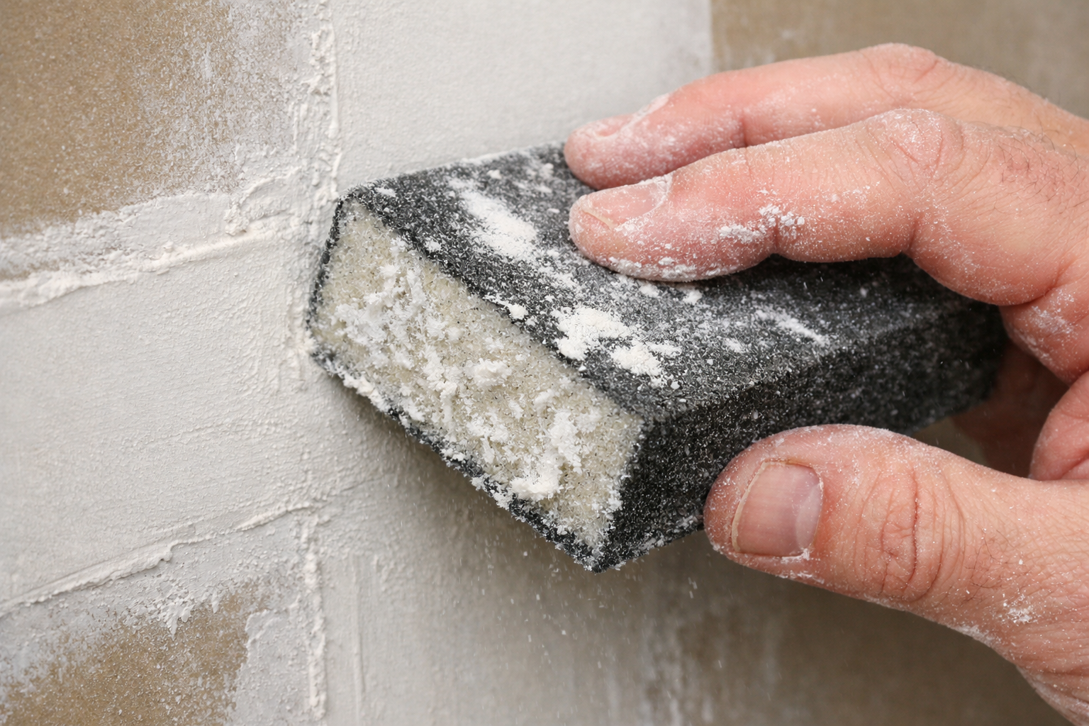 Primer plano del lijado en húmedo de la masilla para juntas de paneles de yeso con una esponja húmeda para alisar las zonas elevadas sin generar polvo.
