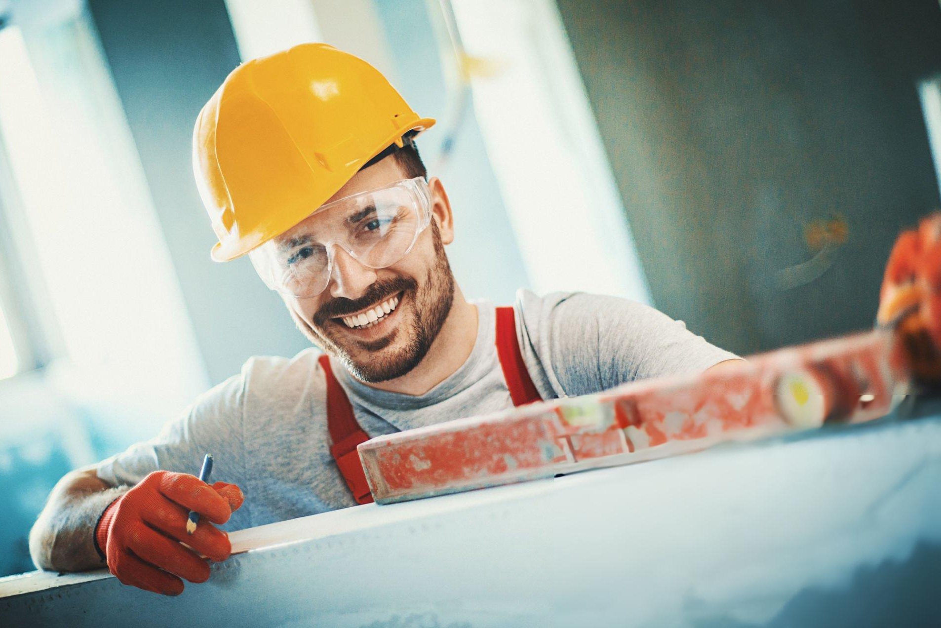 Drywall contractor using a screw gun to hang drywall with an electric sander and dust extractor in the background
